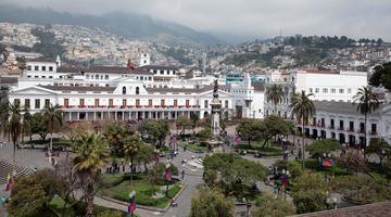 Large white building in Quito with landscape behind it