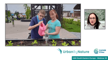 Two young people water plants in a raised bed. 